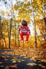 Junge springt auf ein Trampolin, das mit Herbstblättern bedeckt ist, Vereinigte Staaten — Stockfoto