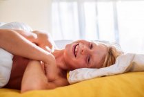 Усміхнений хлопчик лежить у ліжку сміється — стокове фото
