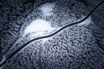 Aerial view on a road winding through snow covered trees in the Austrian Alps. — Stock Photo