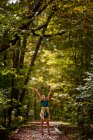 Garota excitada de pé em uma trilha florestal com as mãos no ar, Estados Unidos — Fotografia de Stock