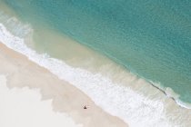 Vista aérea de un hombre parado en la playa junto a una sombrilla, Gold Coast, Queensland, Australia - foto de stock