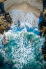 Vista aérea da água azul do oceano esmagando em rochas na praia — Fotografia de Stock