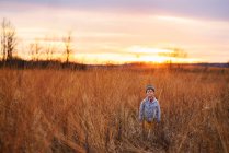 Garçon debout dans un champ au coucher du soleil, États-Unis — Photo de stock