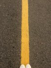 Mulher pés de pé em uma linha amarela na estrada — Fotografia de Stock