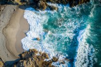 Vista aerea di blu oceano frantumazione acqua a rocce sulla spiaggia — Foto stock