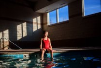 Mädchen sitzt am Rand eines Swimmingpools — Stockfoto