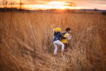 Junge und Mädchen tummeln sich bei Sonnenuntergang auf einem Feld in den Vereinigten Staaten — Stockfoto