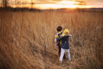 Garçon et fille déconner dans un champ au coucher du soleil, Etats-unis — Photo de stock