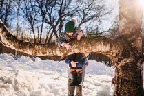 Хлопчик, який взимку допомагає дівчині вилізти на дерево (США). — стокове фото