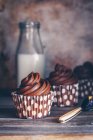 Trois cupcakes au chocolat avec une bouteille de lait — Photo de stock