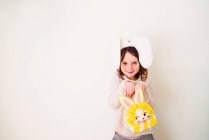 Портрет улыбающейся девушки с кроличьими ушами, держащей кроличью сумку — стоковое фото