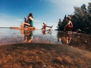Tres niños navegando en un lago en una balsa de madera, Lake Superior, Estados Unidos - foto de stock