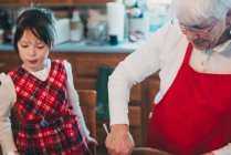 Grandmother teaching her granddaughter to bake — Stock Photo