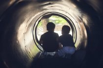 Silhueta de dois meninos brincando em um túnel — Fotografia de Stock