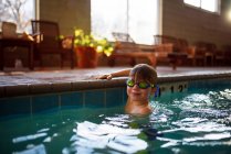 Lächelnder Junge hält sich am Rand eines Schwimmbades fest — Stockfoto