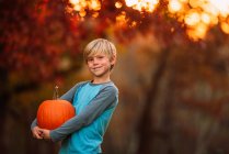 Portrait of a Boy standing in a garden carrying a pumpkin, United States — Stock Photo
