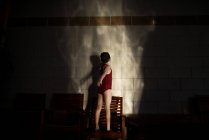 Chica en un traje de baño haciendo sombras contra una pared - foto de stock