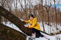 Chica sonriente trepando a un árbol caído, Estados Unidos - foto de stock