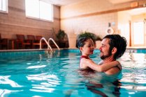 Padre che tiene sua figlia in piscina — Foto stock