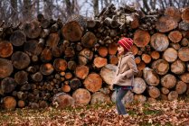 Smiling Girl de pie frente a una pila de madera, Estados Unidos - foto de stock