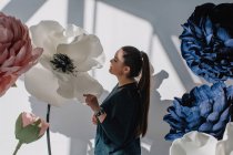 Portrait d'une femme debout à côté de fleurs artificielles géantes — Photo de stock