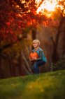 Boy in a garden bending over to pick up a pumpkin, United States — Stock Photo