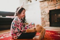Girl wearing bunny ears playing with a soft toy rabbit — Stock Photo