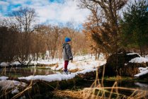 Boy standing on a fallen log in winter, United States — Stock Photo