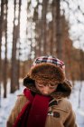 Retrato de um menino na floresta usando um chapéu de inverno e casaco quente — Fotografia de Stock
