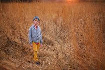 Garçon souriant avec pantalon sale debout dans un champ, États-Unis — Photo de stock