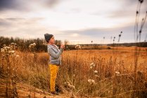 Junge steht auf einem Feld und schaut auf seine Hände, Vereinigte Staaten — Stockfoto
