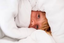 Portrait of a boy wrapped in a duvet — Stock Photo