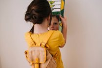 Visão traseira de uma menina olhando para seu reflexo em um espelho — Fotografia de Stock