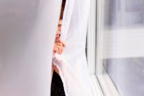 Girl hiding behind a curtain laughing — Stock Photo
