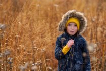 Ritratto di una ragazza in piedi in un campo che mastica un pezzo di erba lunga, Stati Uniti — Foto stock