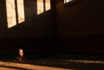 Мальчик плавает в бассейне в тени — стоковое фото