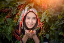 Portrait of a smiling woman holding raw coffee beans, Thailand — Stock Photo