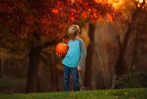 Портрет хлопчика, що стоїть у саду з гарбузом (США). — стокове фото
