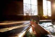 Rapaz agarrado à beira de uma piscina — Fotografia de Stock