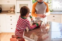 Хлопчик допомагає батькові пекти на кухні — стокове фото