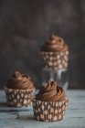 Três cupcakes de chocolate em uma mesa de madeira — Fotografia de Stock