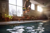 Boy jumping into a swimming pool — Stock Photo