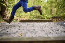 Cropped image of Boy running across a small footbridge — Stock Photo