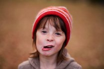 Retrato de uma menina com um chapéu de lã puxando caras engraçadas — Fotografia de Stock