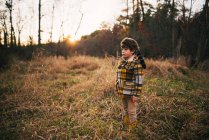 Мальчик, стоящий в лесу осенью, США — стоковое фото