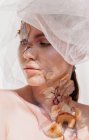 Konzeptuelles Schönheitsporträt einer Frau, die einen Schleier mit getrockneten Blumen im Gesicht und am Hals trägt — Stockfoto