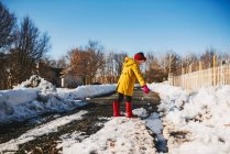 Mädchen spielt an einer Pfütze aus schmelzendem Schnee, Vereinigte Staaten — Stockfoto