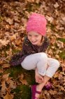 Menina sorridente sentada entre as folhas de outono, Estados Unidos — Fotografia de Stock