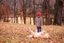 Menina de pé na floresta brincando com seu cão, Estados Unidos — Fotografia de Stock