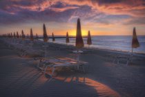 Sonnenliegen und Sonnenschirme am Strand bei Sonnenaufgang, eraclea, italien — Stockfoto